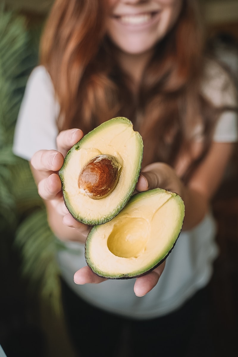 Hand hält eine aufgeschnittene, baumgereifte Avocado